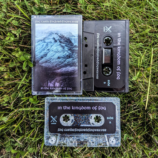 FOG CASTLE / FOGWEAVER / FOGLORD "In The Kingdom Of Fog" cassette tape, black cassette with printed sticker label, glitter cassette with printed sticker label, and Norelco case with printed j-card, on a bed of grass